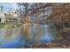 Picturesque pond view from the property with a screened-in porch and treed landscape at 6740 Mountain Lake Ln, Cumming, GA 30028