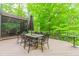 Wooden deck featuring dining area with a large umbrella, screened porch, and green scenery at 10490 Cranchester Way, Alpharetta, GA 30022