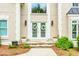 Up-close view of a front entrance features decorative double doors, stone steps, and manicured landscaping at 10490 Cranchester Way, Alpharetta, GA 30022