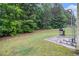 Concrete patio with grill and pull-up bar, leading to a well-maintained green backyard with mature trees and landscaping at 6664 Saint Jude Dr, Fairburn, GA 30213