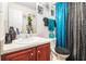 Bathroom vanity with red wooden cabinets, a decorative mirror, and turquoise shower curtain offering plenty of storage space at 6664 Saint Jude Dr, Fairburn, GA 30213