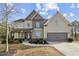 Two-story home featuring a well-manicured front yard, attached garage, and charming covered porch at 2496 Osceola Rd, Lithonia, GA 30058