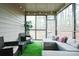 Enclosed patio featuring comfortable seating, artificial turf, and view of the wooded backyard at 2496 Osceola Rd, Lithonia, GA 30058