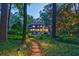 Stone pathway through a lush backyard, leading to a well-lit home and outdoor seating area at 3117 W Roxboro Ne Rd, Atlanta, GA 30324