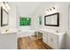 A well-lit bathroom featuring dual vanities, wood look floors, and a soaking tub beneath a bright window at 610 Golden Meadows Ln, Suwanee, GA 30024