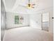 Bright bedroom boasts a tray ceiling with fan, neutral carpet, and a window with a view at 610 Golden Meadows Ln, Suwanee, GA 30024