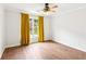 Bedroom featuring wood floors, a ceiling fan, and a bright window dressed with yellow drapes at 610 Golden Meadows Ln, Suwanee, GA 30024