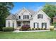 Charming two-story home with a manicured lawn, lush landscaping, and a classic white brick facade at 1640 Settindown Dr, Roswell, GA 30075