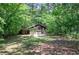 A weathered outbuilding with a garage door nestled amongst dense trees and foliage at 3156 Pope Rd, Douglasville, GA 30135