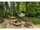 Secluded backyard area featuring a fire pit, shed, table and chairs, and wooded surroundings at 5600 Surrey Ct, Alpharetta, GA 30009