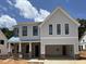 Two-story home featuring light gray siding, a two-car garage, brick accents, and black trimmed windows at 5627 Meadowstone Walk, Kennesaw, GA 30152