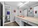 Neutral toned bathroom with an extended vanity and large framed mirror with decorative sports themed art at 450 Bay Grove Se Rd, Loganville, GA 30052