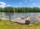 Wooden dock on a tranquil lake, surrounded by lush green trees and blue skies at 450 Bay Grove Se Rd, Loganville, GA 30052