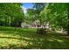 Spacious backyard features lush green lawn, mature trees, and a charming white home with a stone patio at 50 Stonington Pl, Marietta, GA 30068