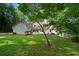 Spacious backyard features lush green lawn, mature trees, and a charming white home with a stone patio at 50 Stonington Pl, Marietta, GA 30068