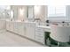 Bright bathroom featuring a white vanity with double sinks and a white leather chair with makeup organizer at 719 Elizabeth Trl, Woodstock, GA 30189