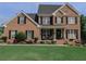 Charming brick home with a manicured lawn, black shutters, and inviting front porch seating at 1365 Juniper Springs Trl, Loganville, GA 30052