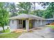 Charming single-story home with gray brick, covered porch, yellow door, and mature trees in a quiet residential neighborhood at 2564 Riggs Dr, East Point, GA 30344