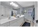 Bathroom with double vanity, white cabinets, large mirror and abundant lighting at 4012 Ironhill Ln, Woodstock, GA 30189