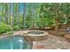 Picturesque waterfall cascading into a stone hot tub next to the swimming pool, surrounded by mature trees at 4012 Ironhill Ln, Woodstock, GA 30189