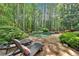 Beautiful kidney-shaped pool with stone patio and lounge chairs, surrounded by lush greenery for ultimate privacy at 4012 Ironhill Ln, Woodstock, GA 30189