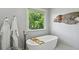 Soaking tub in bright bathroom with freestanding faucet, wooden caddy, and decorative fish at 129 2Nd Se Ave, Atlanta, GA 30317