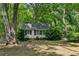 Charming house nestled among mature trees with simple white siding and black shutters at 4202 Maplewood Dr, Decatur, GA 30035