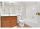 Bright bathroom featuring wood cabinet sink, toilet, bathtub with white tiles and a large mirror at 991 Lisa Kay Dr, Lawrenceville, GA 30046