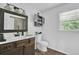 Bathroom featuring a wood vanity, decorative mirror, and natural light, complemented by tile flooring at 1315 Arden Sw Dr, Marietta, GA 30008