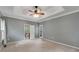 Spacious bedroom with tray ceilings, neutral paint, ceiling fan, and view to a study or office at 2350 Shore View Nw Way, Suwanee, GA 30024