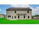 Backyard view of two-story house with green grass, a small patio and neutral siding at 2447 Cadenza Cir, Dacula, GA 30019