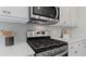 Close up on the stainless steel oven and microwave above white countertops, drawers, and cabinets at 2447 Cadenza Cir, Dacula, GA 30019