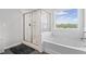 Modern bathroom featuring a walk-in shower, soaking tub, and a bright window at 7095 Evening Dew Dr, Cumming, GA 30028
