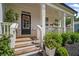 Inviting front porch with flowers, black door, and fresh landscaping at 7095 Evening Dew Dr, Cumming, GA 30028