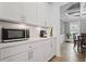 Charming kitchen area with white cabinets, a microwave, and view of a dining area at 7095 Evening Dew Dr, Cumming, GA 30028