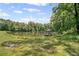 Scenic view of a tranquil pond with a gazebo on a dock, surrounded by lush greenery at 7095 Evening Dew Dr, Cumming, GA 30028
