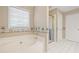 Bright bathroom featuring a soaking tub, tiled floor, and a glass-enclosed shower at 1065 Dalby Way, Austell, GA 30106