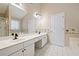 Bathroom with dual sinks, white tile floors, a large mirror, and decorative wallpaper at 1065 Dalby Way, Austell, GA 30106