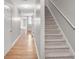 Inviting hallway with wood floors leads to carpeted stairs and a glimpse of a sunlit living space at 132 Tara Commons Dr, Loganville, GA 30052