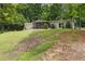 Single-story home with screened porch surrounded by lush greenery on a sloped lot at 1447 High Sierra Dr, Lawrenceville, GA 30043
