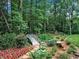 Charming backyard with a small bridge, colorful flowers, and manicured shrubs at 3625 Tuxedo Nw Rd, Atlanta, GA 30305