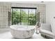 Elegant bathroom featuring a freestanding tub, a modern chair, and a large window with a lush view at 3625 Tuxedo Nw Rd, Atlanta, GA 30305