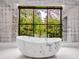 Luxurious bathroom featuring a soaking tub and a large window with lush green views at 3625 Tuxedo Nw Rd, Atlanta, GA 30305
