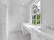 All-white bathroom features marble countertop, storage, and a large window for natural light at 3625 Tuxedo Nw Rd, Atlanta, GA 30305