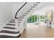 Light-filled foyer with dark and white staircase and light hardwood floors leading to an open living space at 3625 Tuxedo Nw Rd, Atlanta, GA 30305