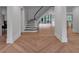 Bright foyer featuring chevron wood floors, staircase with black banister and light walls with large windows throughout at 3625 Tuxedo Nw Rd, Atlanta, GA 30305