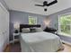 Cozy bedroom features two windows, ceiling fan, and a light green bedspread at 11415 Hutcheson Ferry Rd, Chattahoochee Hills, GA 30268