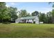 A charming home with a metal roof sits on a sprawling lawn. The house features a two car garage and classic architecture at 11415 Hutcheson Ferry Rd, Chattahoochee Hills, GA 30268