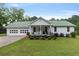 Charming home featuring a metal roof, two-car garage and a cozy front porch, surrounded by a well maintained lawn at 11415 Hutcheson Ferry Rd, Chattahoochee Hills, GA 30268