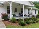 Close up of the front porch, with beautiful landscaping and inviting details with seating and plants in pots at 11415 Hutcheson Ferry Rd, Chattahoochee Hills, GA 30268